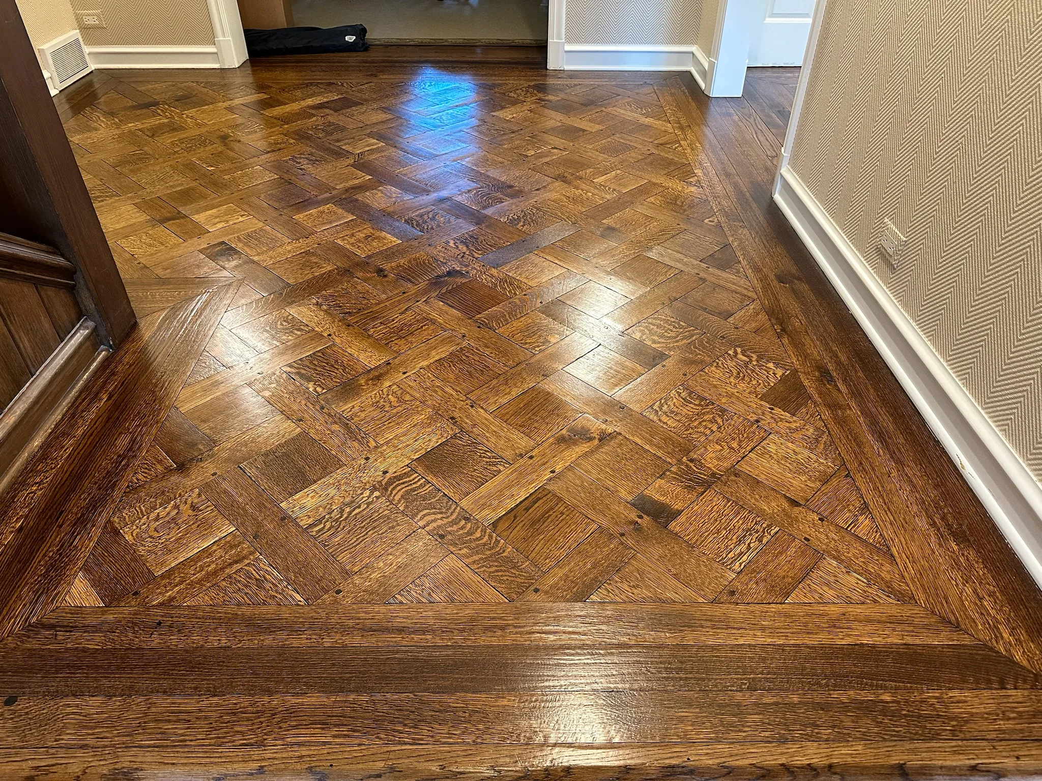 Close-up of a beautifully designed parquet hardwood floor with intricate patterns, adding elegance and warmth to a home interior.